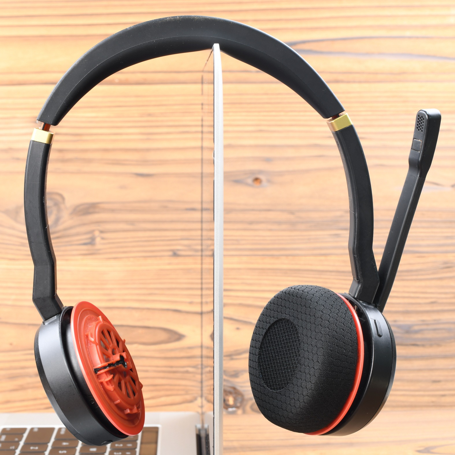Schwarzer Headset mit orangefarbenen Akzenten ruht auf einem Laptop vor Holz.