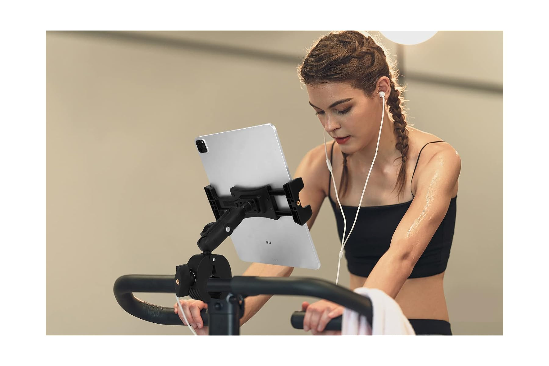 Eine Frau mit Zöpfen trainiert auf einem Heimtrainer, hört Musik über Ohrhörer.