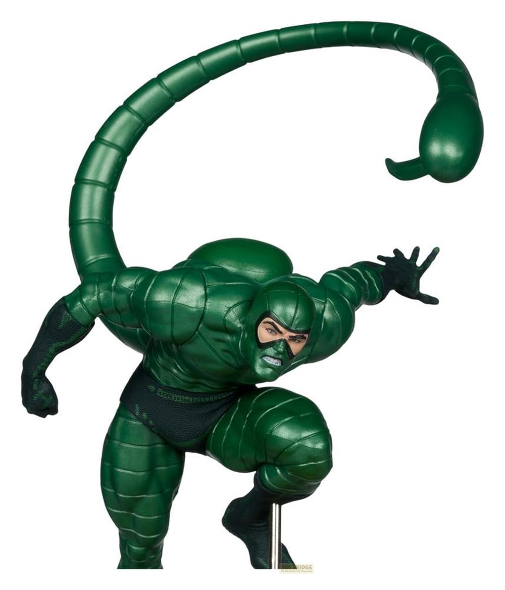Eine grüne Figur mit einem Skorpionstachel steht in einer Hocke.