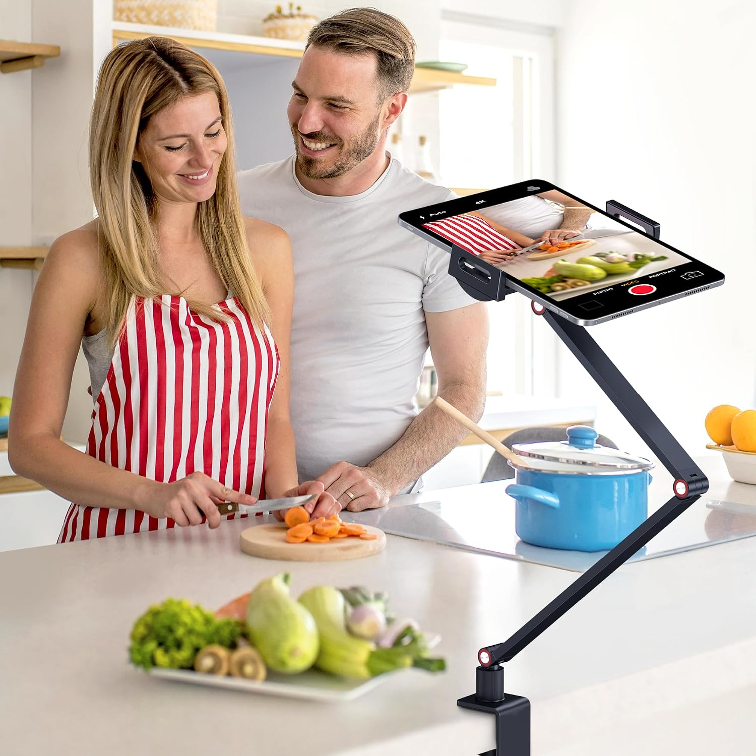 Mann und Frau kochen und filmen sich auf einem Tablet in der Küche.