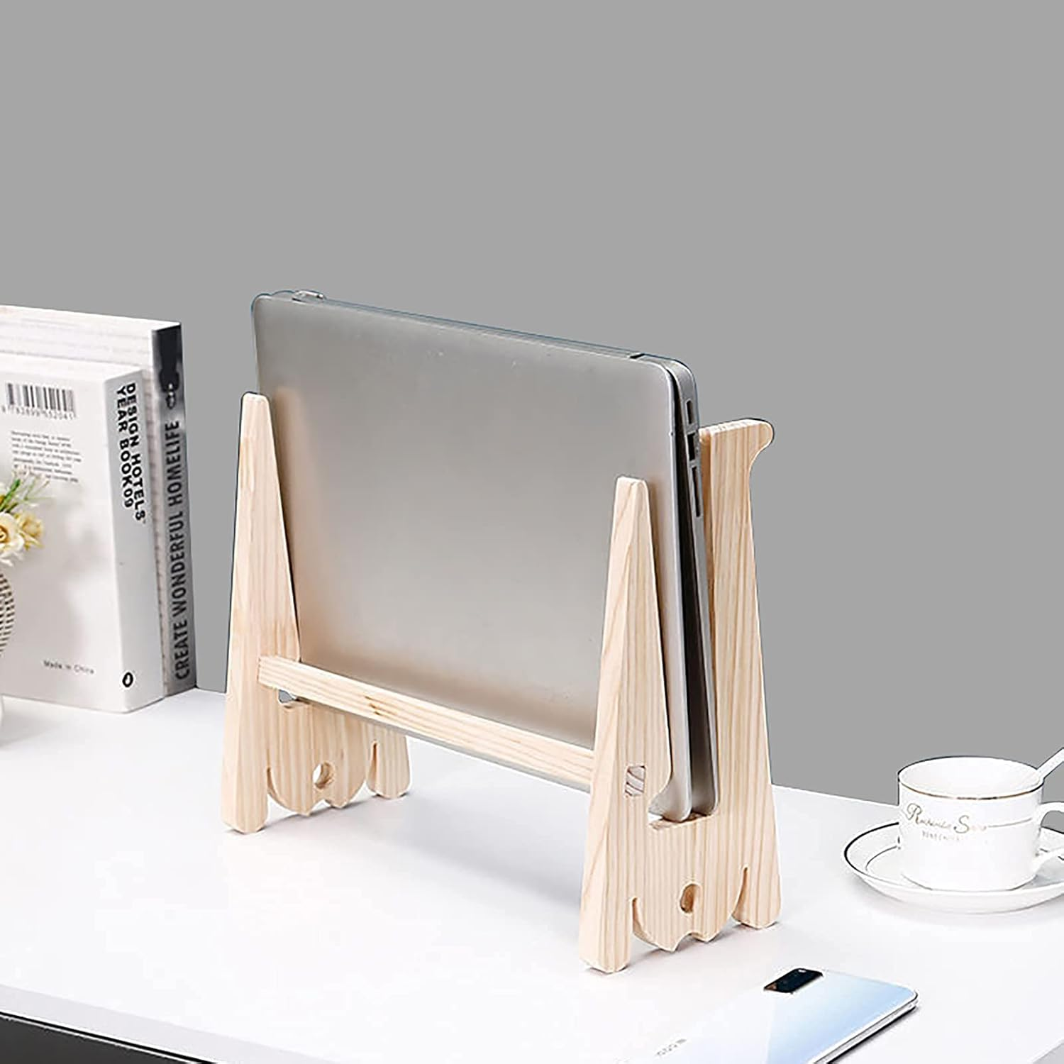 Ein hölzerner Tablet-Ständer mit einem Tablet, Büchern und einer Tasse auf einem Schreibtisch.
