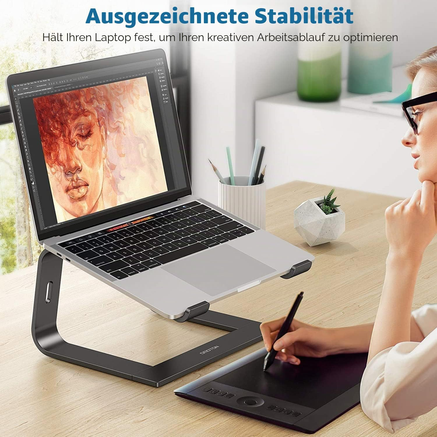 Frau arbeitet am Laptop und Zeichentablett auf einem Schreibtisch.