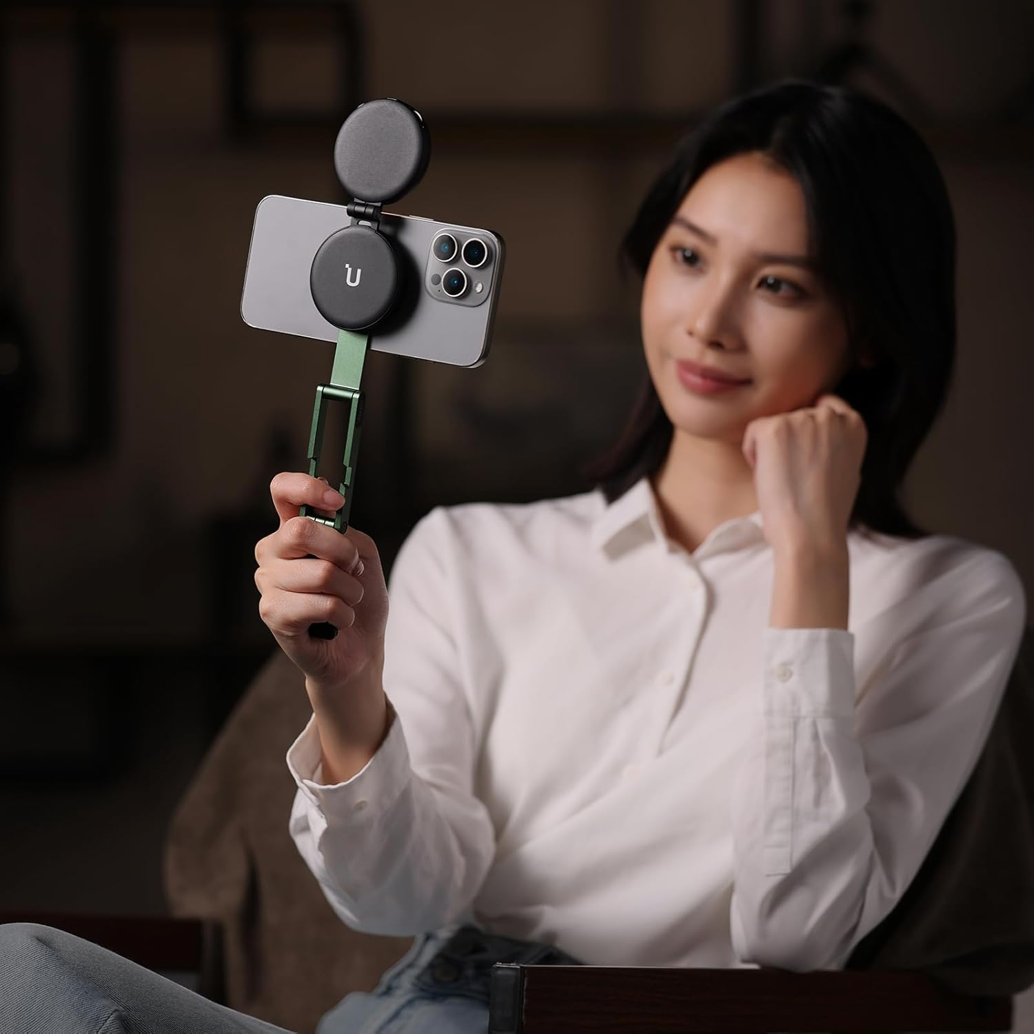 Una mujer sostiene un teléfono inteligente con luz de anillo y gimbal.