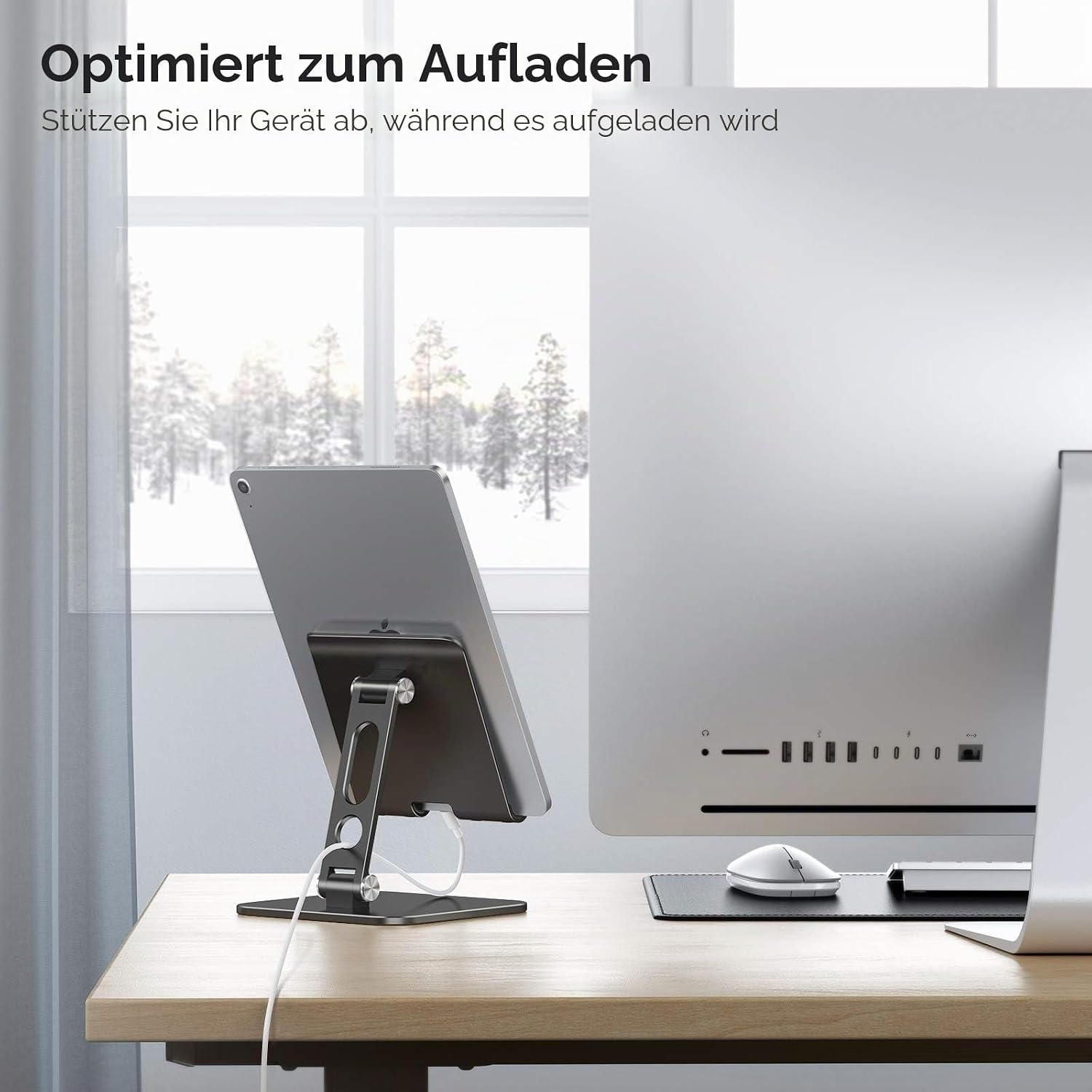 Ein Tablet auf einem Ständer lädt, neben einem Computer.