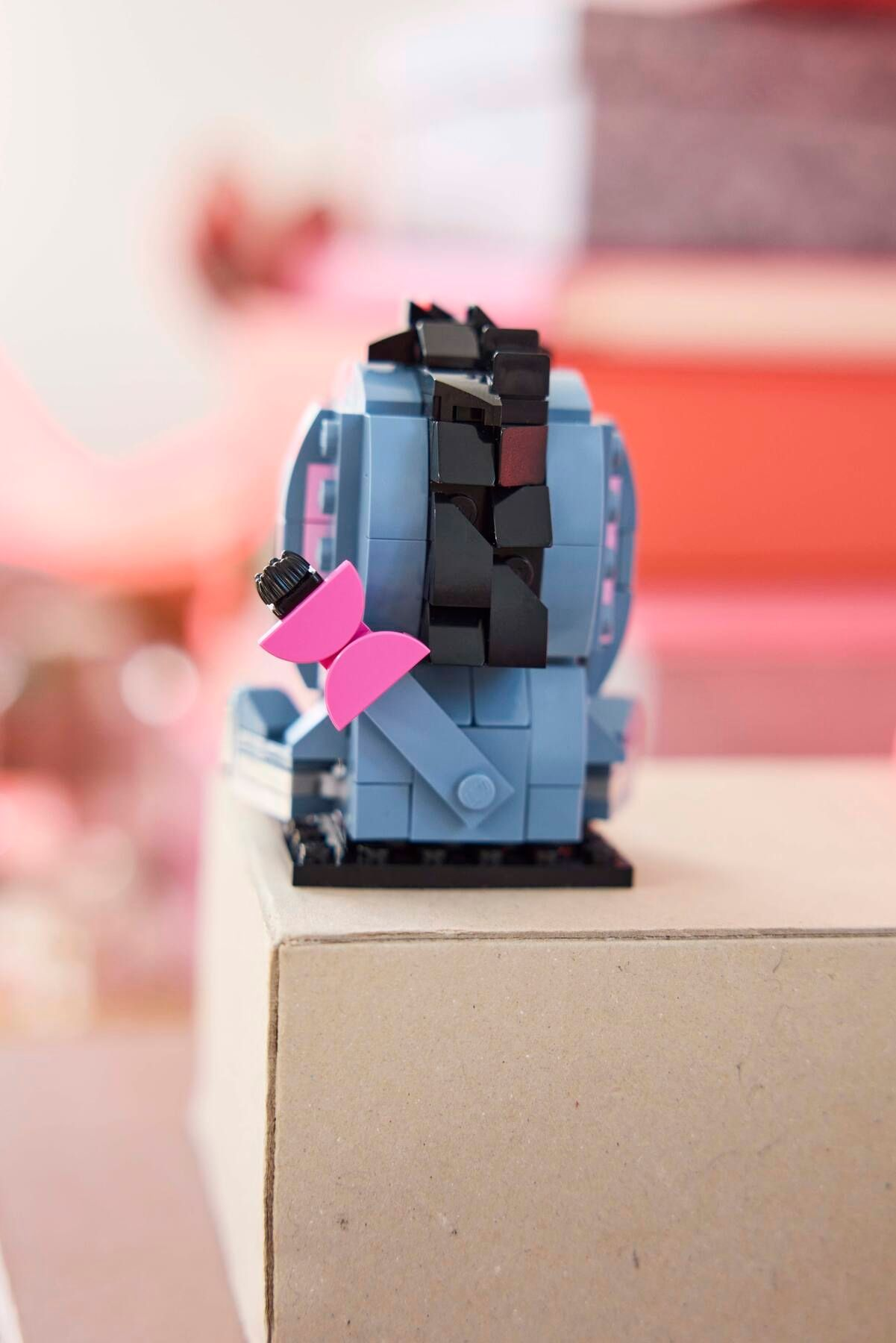 Siyah ve pembe detaylı mavi bir Lego nesnesi karton kutunun üzerinde duruyor.