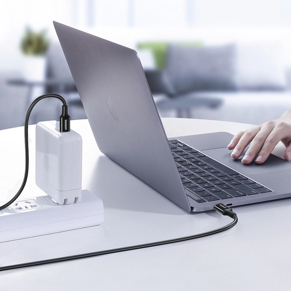 Czarny kabel USB-C łączy biały zasilacz z laptopem.