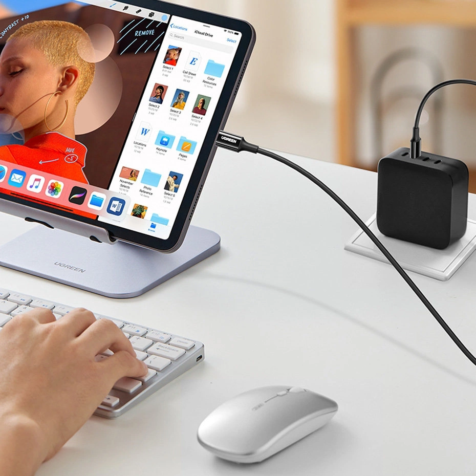 Tablet podłączony do czarnej ładowarki kablem USB.