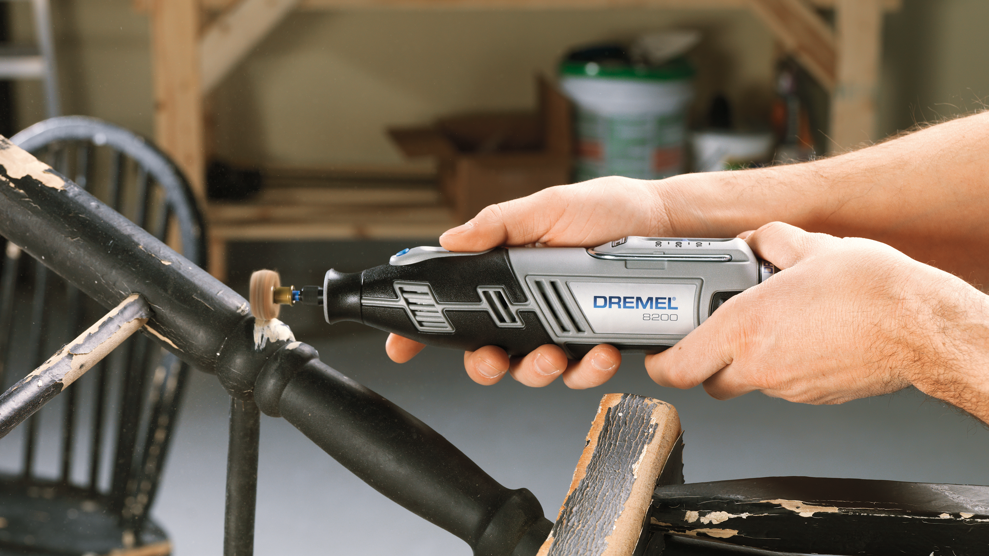 Mann bearbeitet altes Holz mit einem Dremel-Werkzeug in einer Werkstatt.
