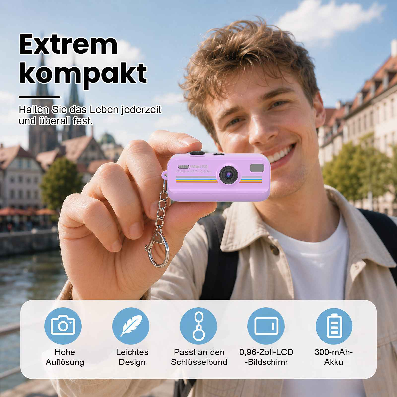 Mann hält eine lila Mini-Kamera mit Schlüsselanhänger, Hintergrund unscharf.