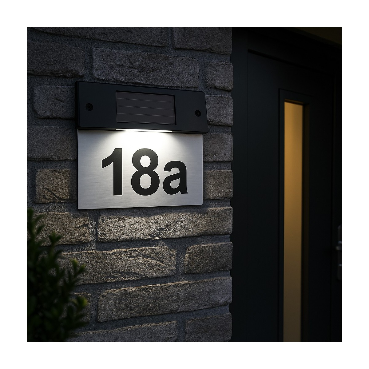 Verlicht huisnummerbord 18a op bakstenen muur naast een donkere deur.