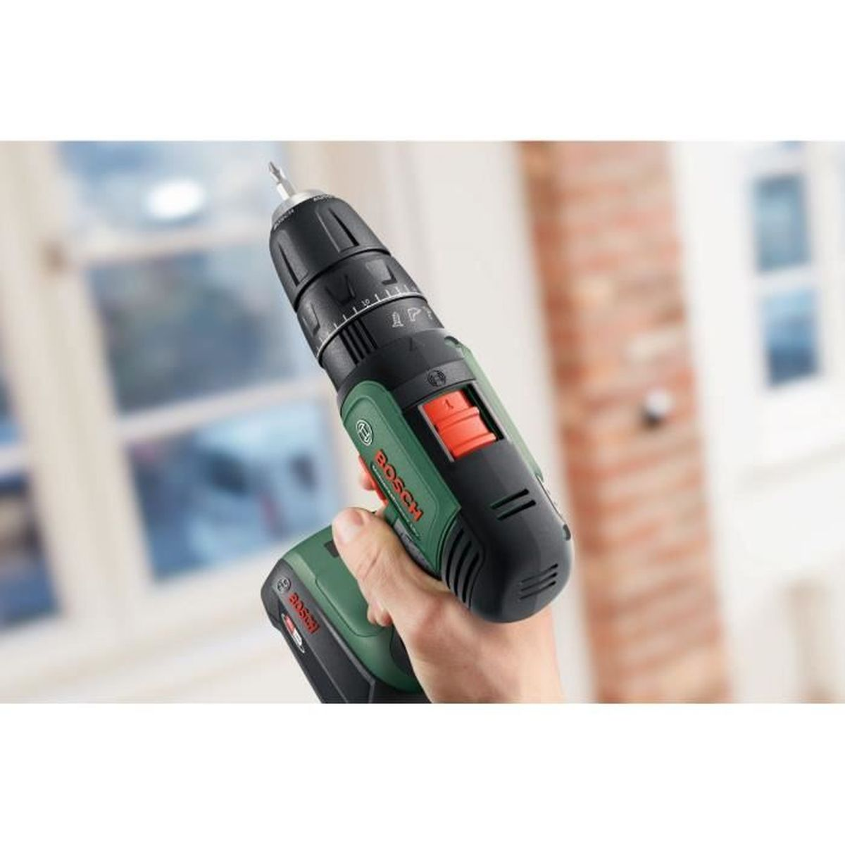 Una mano tiene un trapano a batteria Bosch nero e verde con punta argentata.