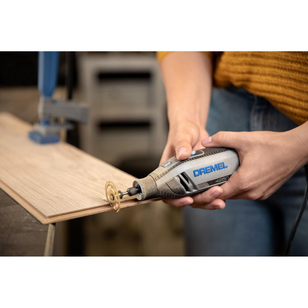 Eine Person nutzt ein Dremel-Multifunktionswerkzeug, um eine Nut in ein Holzbrett zu fräsen.