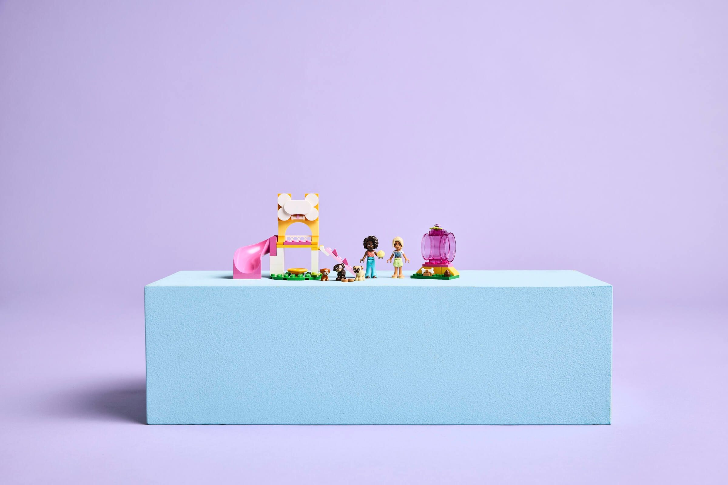 Set di gioco Lego Friends con due mini-doll, tre cani, una torre con scivolo giallo e un tunnel rosa.