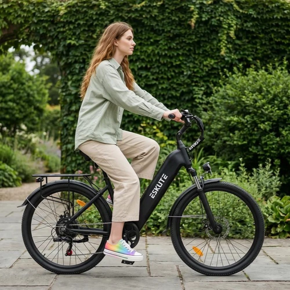 Una donna con una camicia verde guida una e-bike nera Eskute su un sentiero lastricato.
