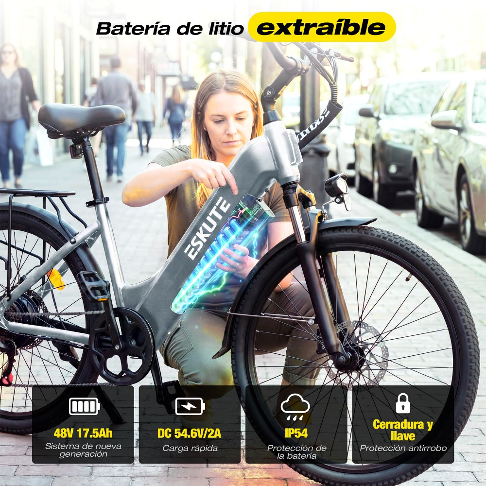 Una mujer extrae la batería del cuadro de una bicicleta eléctrica plateada en una calle.