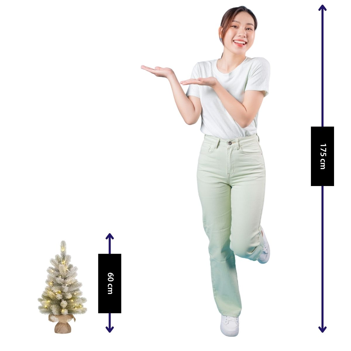 A woman gesturing toward a 60 cm small lit Christmas tree, comparing it to her 175 cm height.