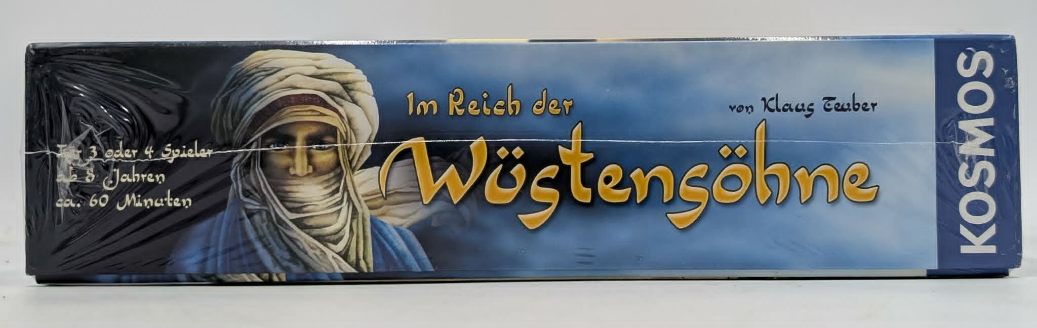 Seitenansicht der Brettspielbox "Im Reich der Wüstensöhne" mit einem Porträt und dem Verlagslogo Kosmos.