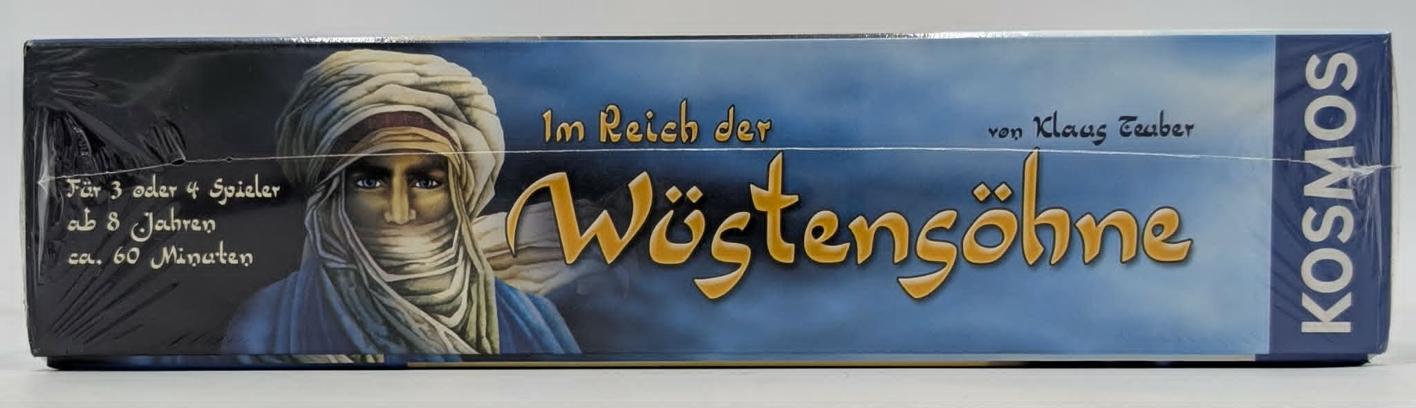 Seitenansicht der Brettspielbox "Im Reich der Wüstensöhne" mit einem Porträt und goldenen Schriftzügen.