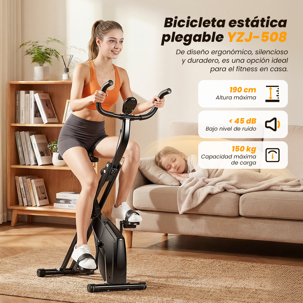 Una mujer hace ejercicio en una bicicleta estática negra en casa mientras un niño duerme.