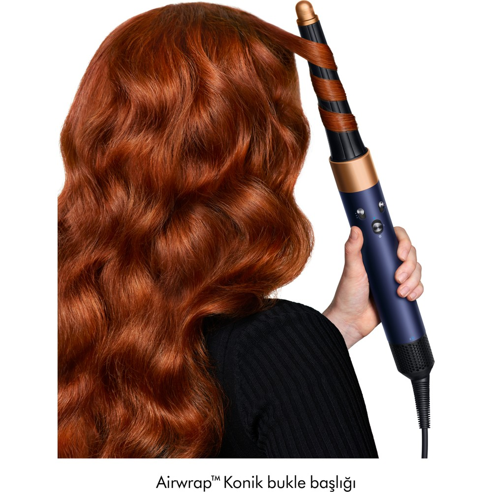Una donna acconcia i capelli rossi usando un arricciacapelli blu e oro rosa.