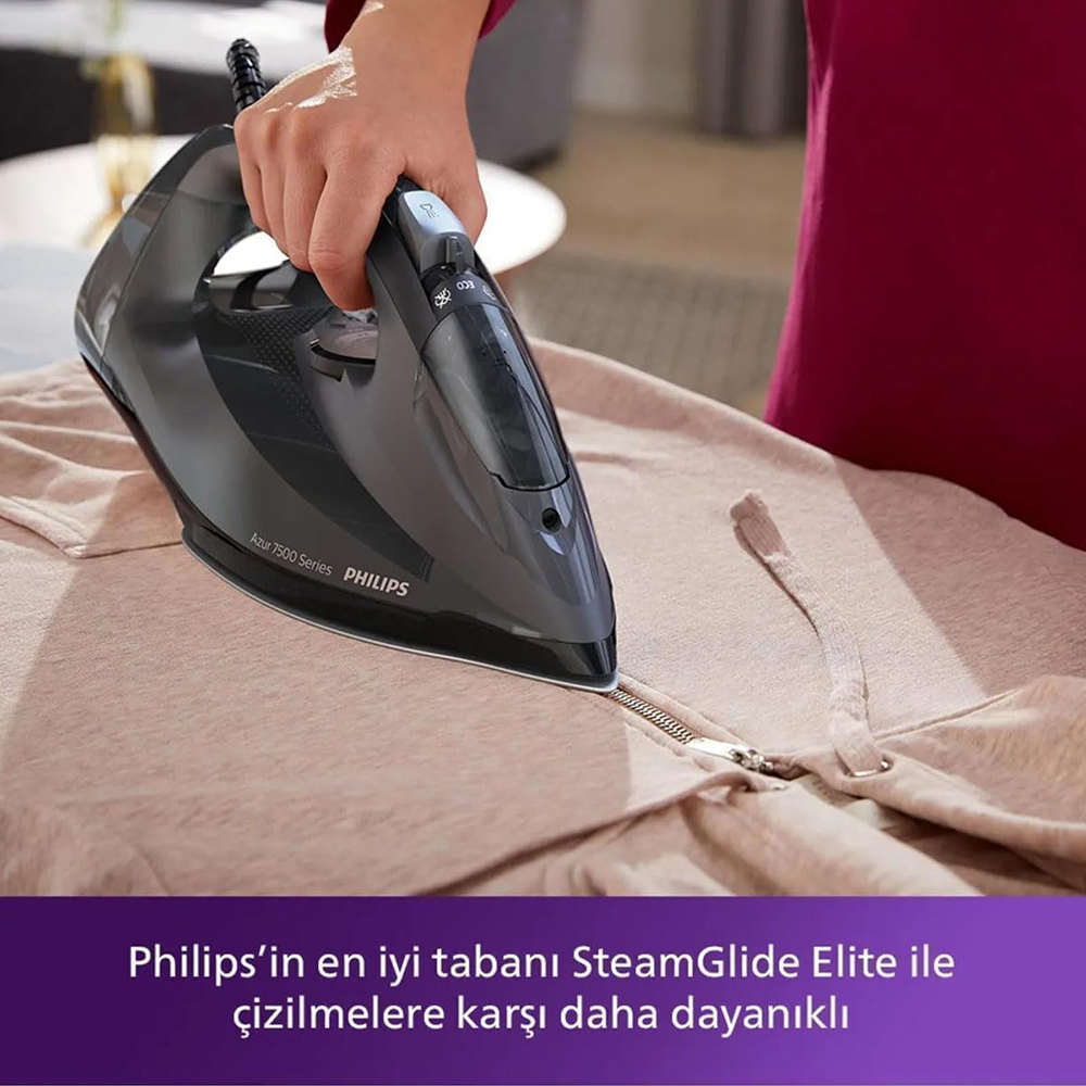Siyah Philips buharlı ütü ile bej rengi bir kıyafeti ütüleyen kişi.