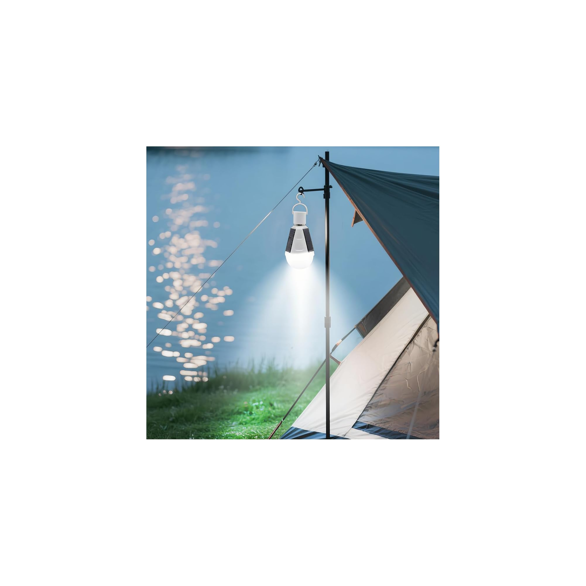 Eine leuchtende Campinglaterne hängt an einer Stange neben einem Zelt am See in der Dämmerung.