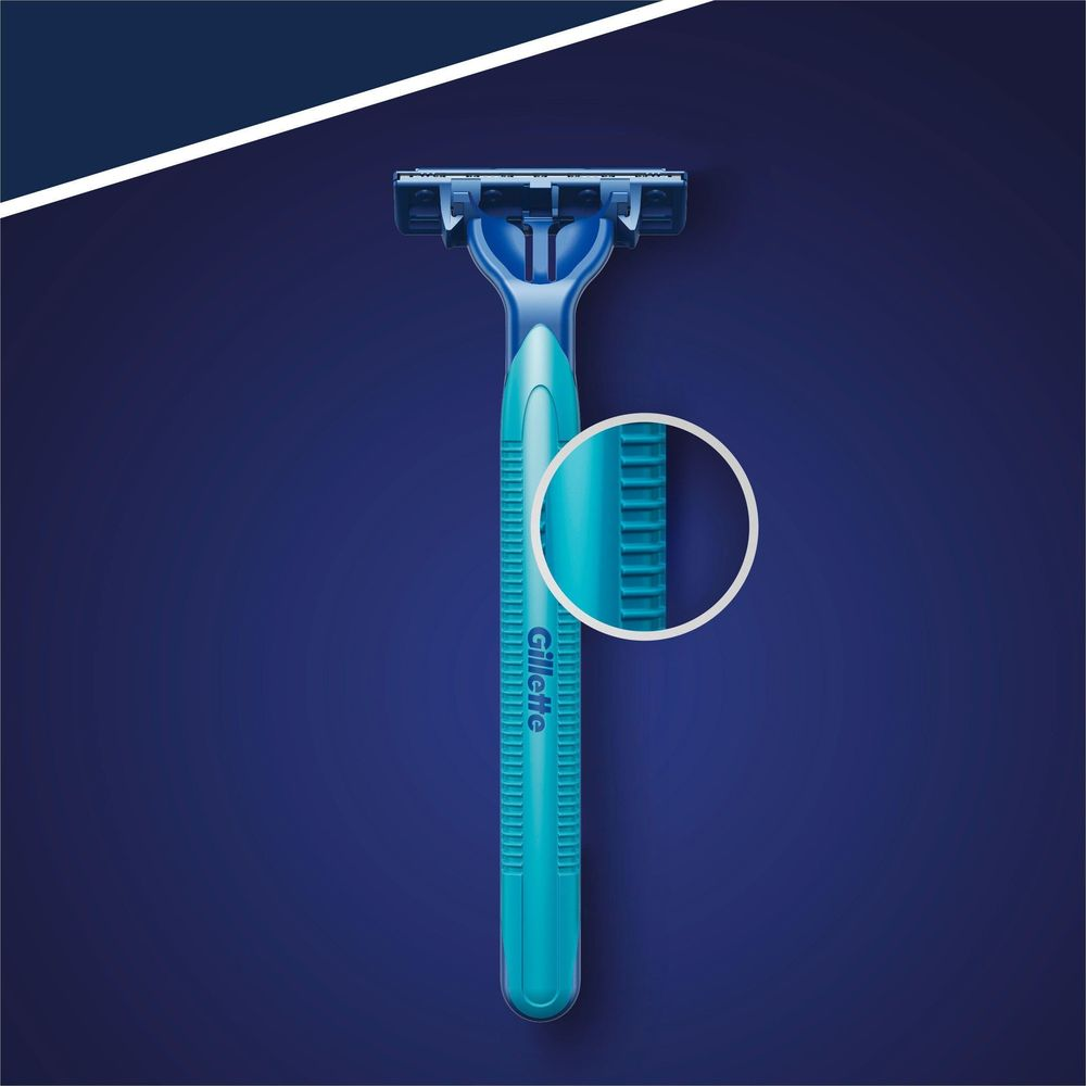 Un rasoio usa e getta Gillette blu su sfondo blu scuro con uno zoom circolare che mostra la texture dell'impugnatura.