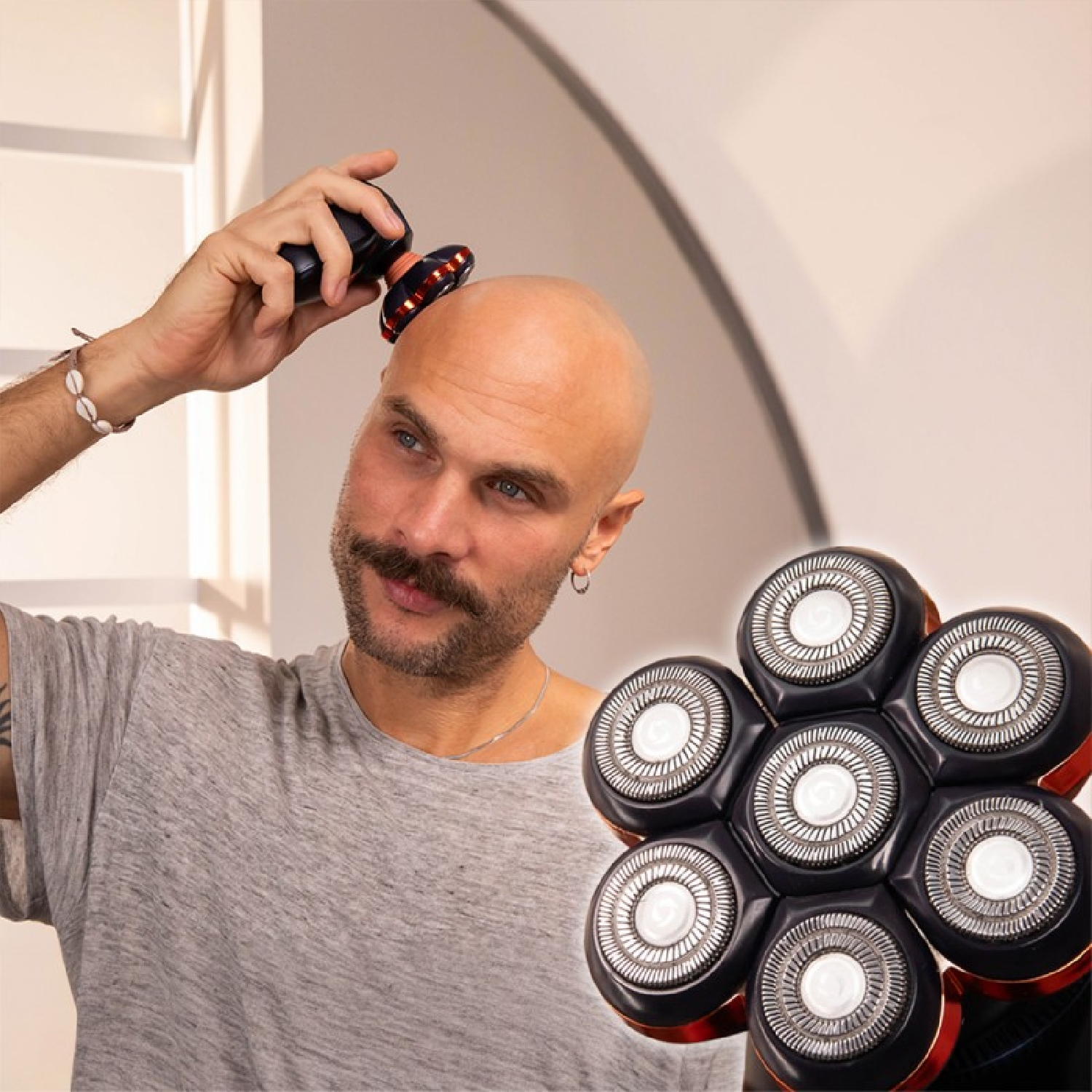 Un uomo calvo si rade la testa con un rasoio elettrico a sei teste in un ambiente interno.