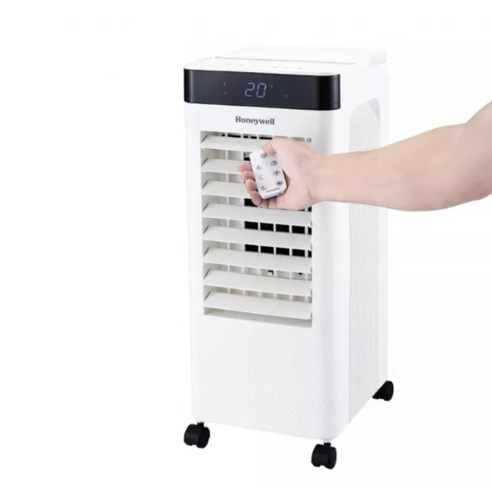 Ręka trzyma pilota przed białym, mobilnym klimatyzatorem Honeywell na kółkach z cyfrowym wyświetlaczem.