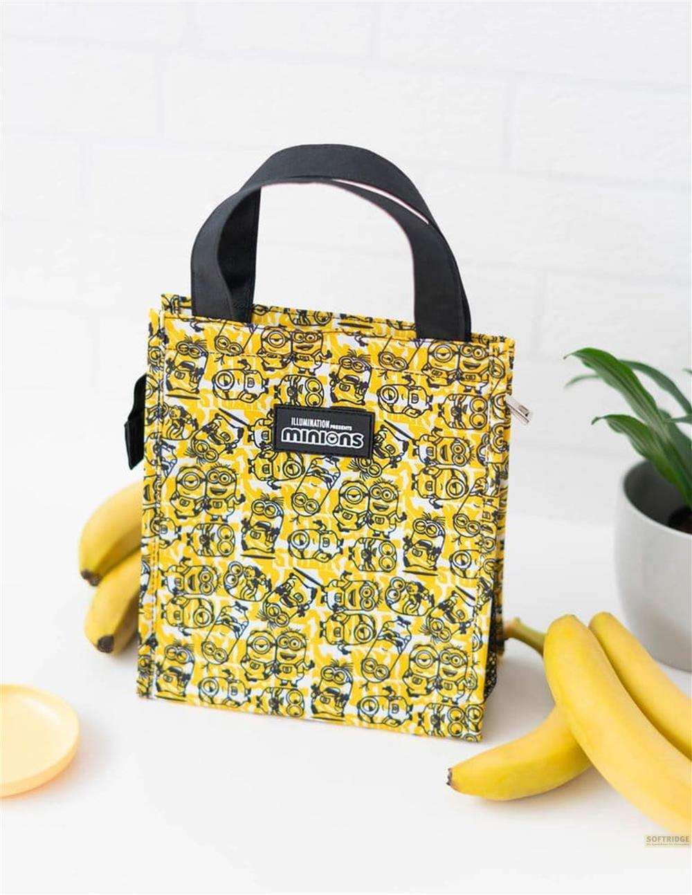 Gelbe Minions-Tragetasche auf weißem Tisch mit Bananen und Pflanze.