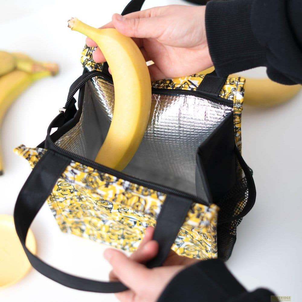 Eine Person legt eine gelbe Banane in eine schwarz-gelb gemusterte Tasche.