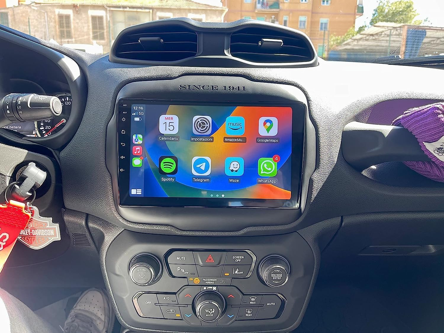 Cruscotto di un'auto con un grande schermo touch centrale che mostra varie icone di app.