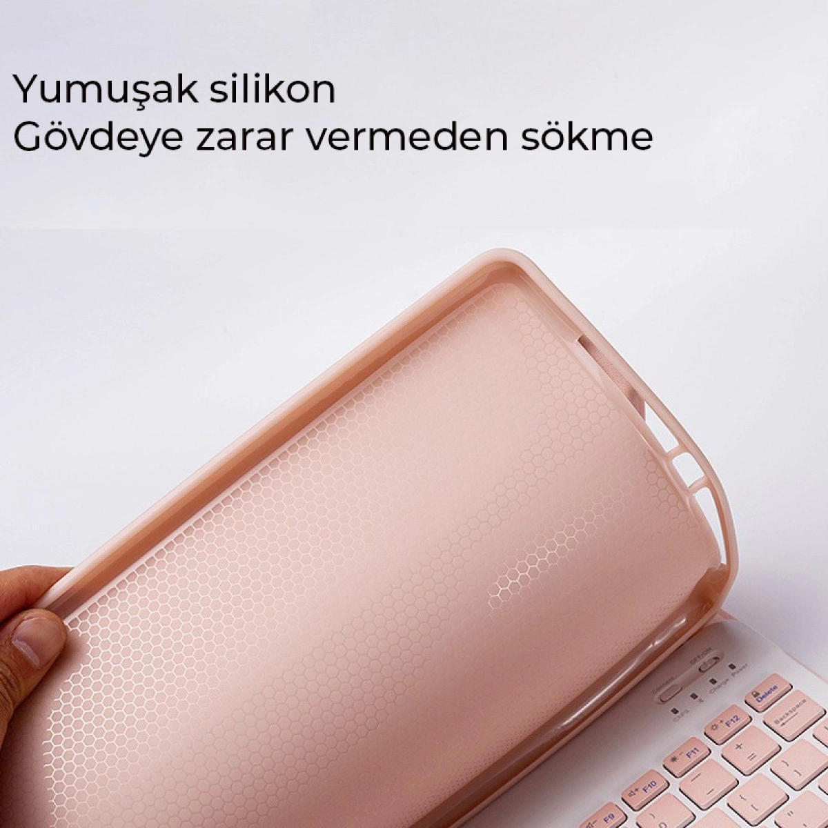 Bir el, petek desenli yumuşak, pembe silikon klavye kılıfını kaldırıyor.