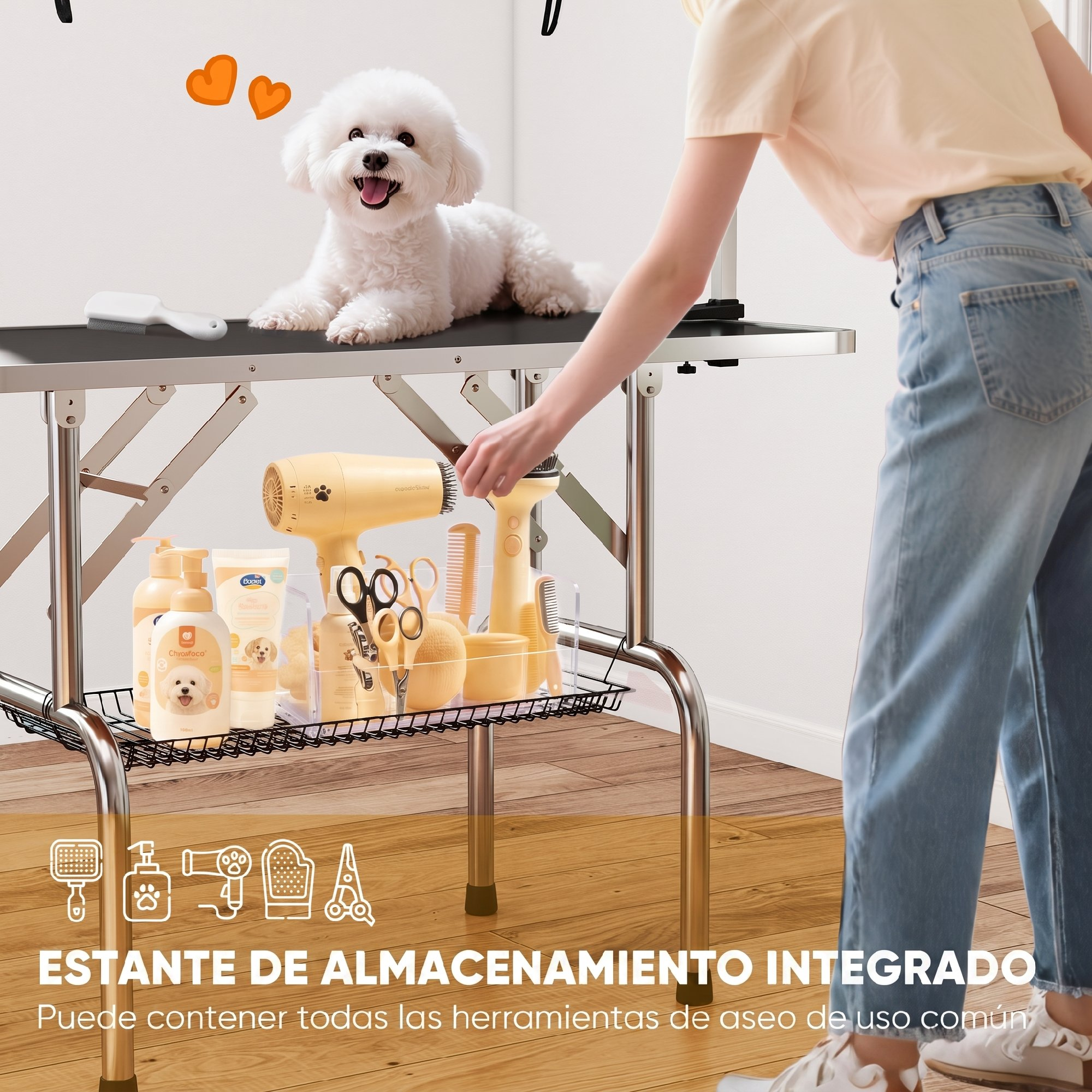 Un caniche blanco está sentado en una mesa de aseo con herramientas en el estante inferior y una persona al lado.