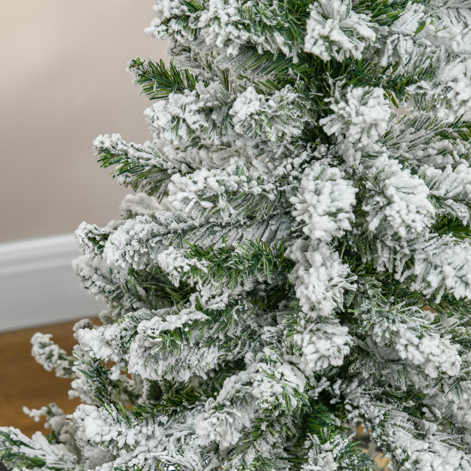 Un árbol de Navidad artificial con una capa de nieve blanca espesa en sus ramas verdes.