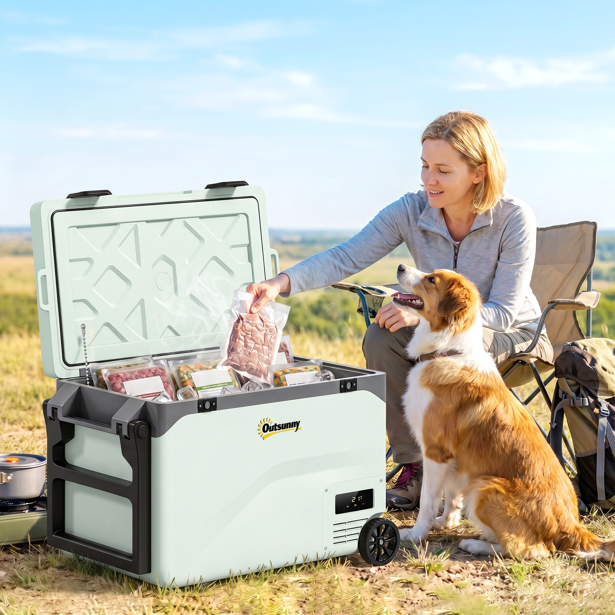 Mujer sentada al aire libre en silla de camping, sacando carne de nevera portátil, perro al lado.