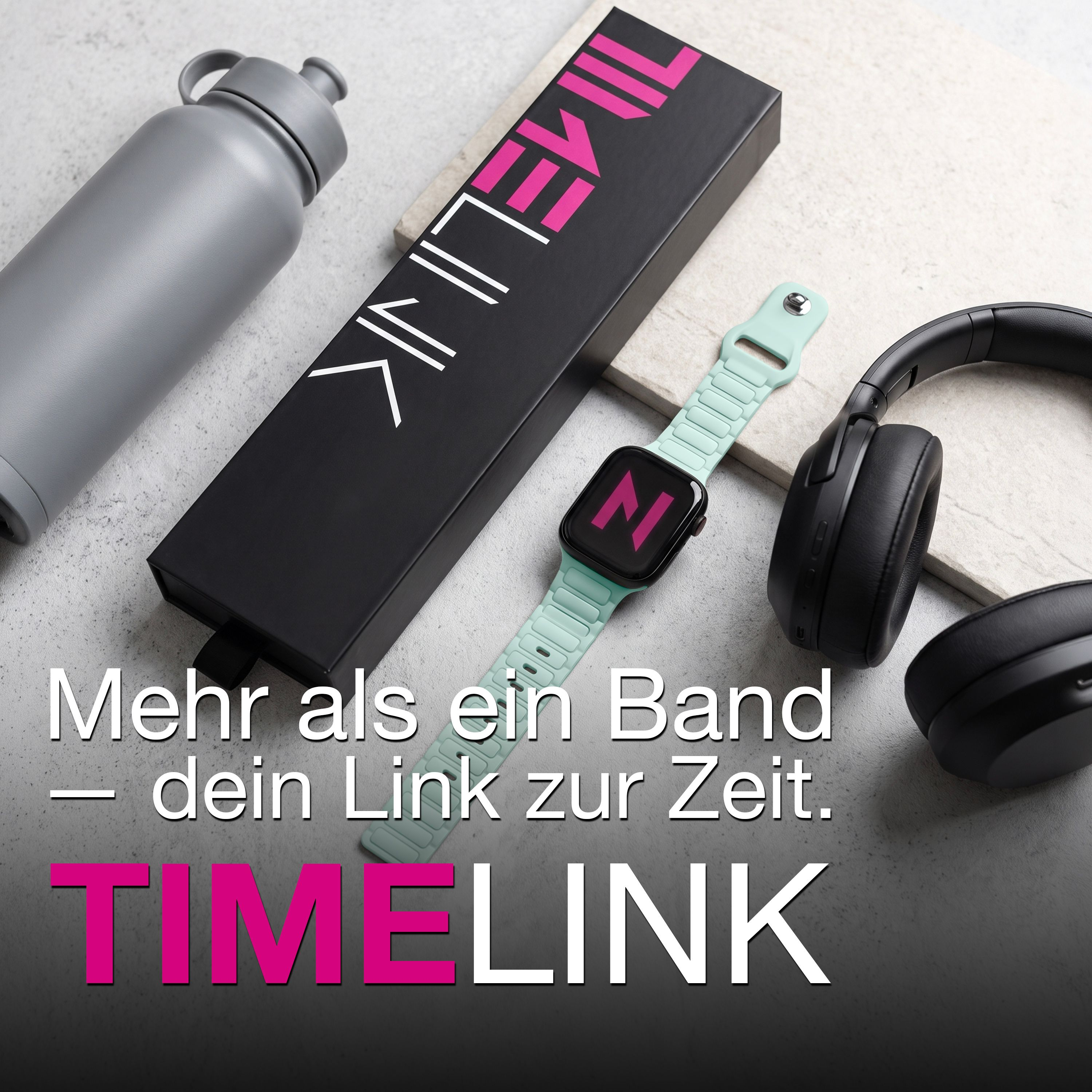 Graue Trinkflasche, schwarze Schachtel, mintgrüne Smartwatch und schwarze Kopfhörer auf hellem Untergrund.