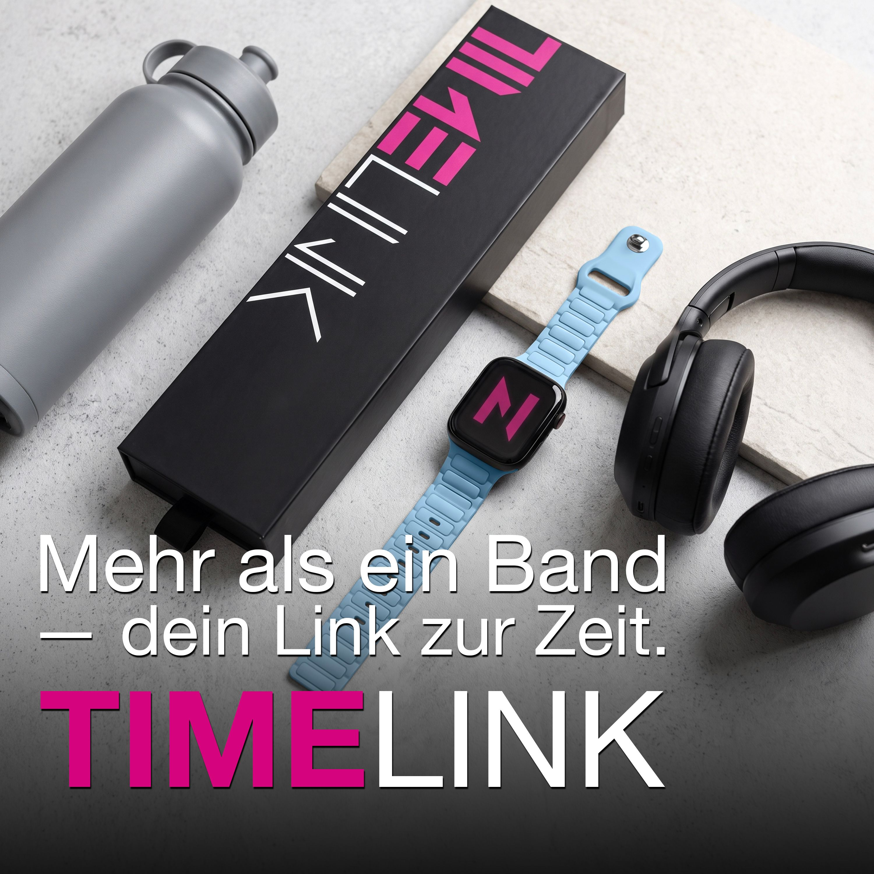Eine graue Trinkflasche, eine schwarze Box, eine hellblaue Smartwatch und schwarze Kopfhörer auf einem Steintisch.