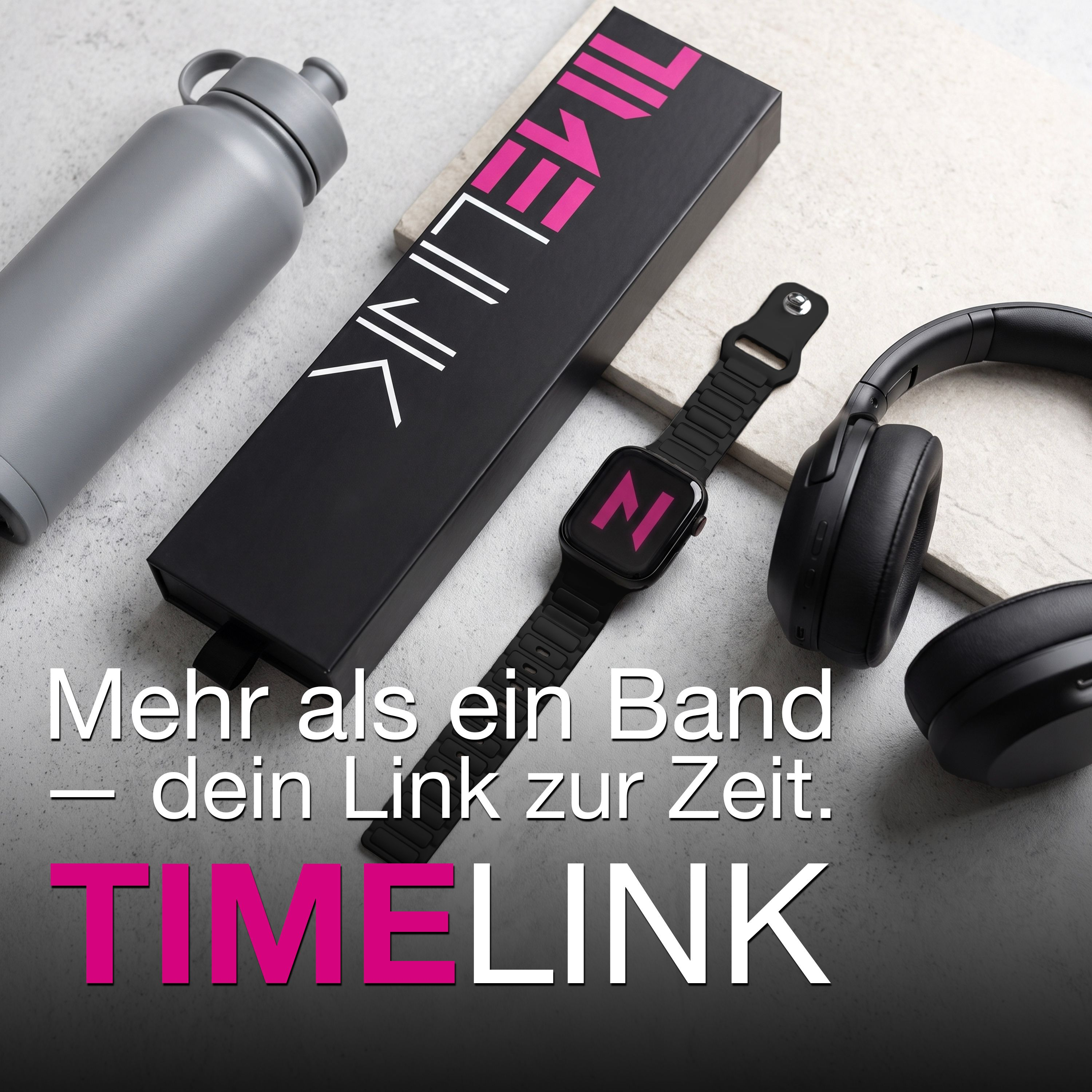 Eine graue Trinkflasche, eine schwarze Schachtel, eine Smartwatch und Kopfhörer liegen auf einer Steinplatte.