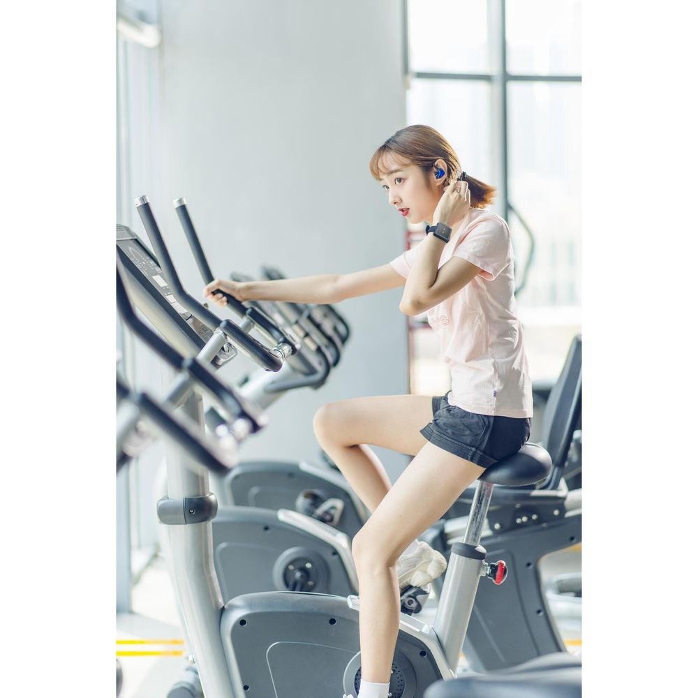 Una mujer con ropa deportiva hace ejercicio en una bicicleta estática en un gimnasio.