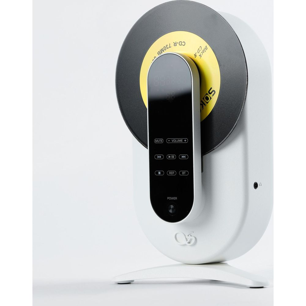 Un reproductor de CD vertical blanco y negro sobre una superficie blanca con un CD amarillo insertado.