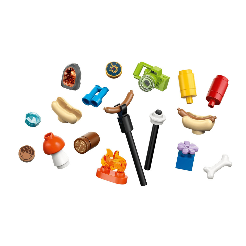 Varios accesorios de camping LEGO coloridos como una fogata, perritos calientes, cámara y prismáticos sobre fondo blanco.