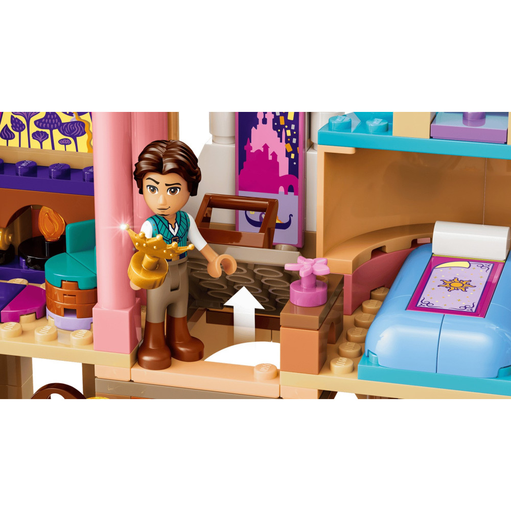 Figurka Lego trzyma złotą koronę obok niebieskiego łóżka i półek w kolorowym zamku.
