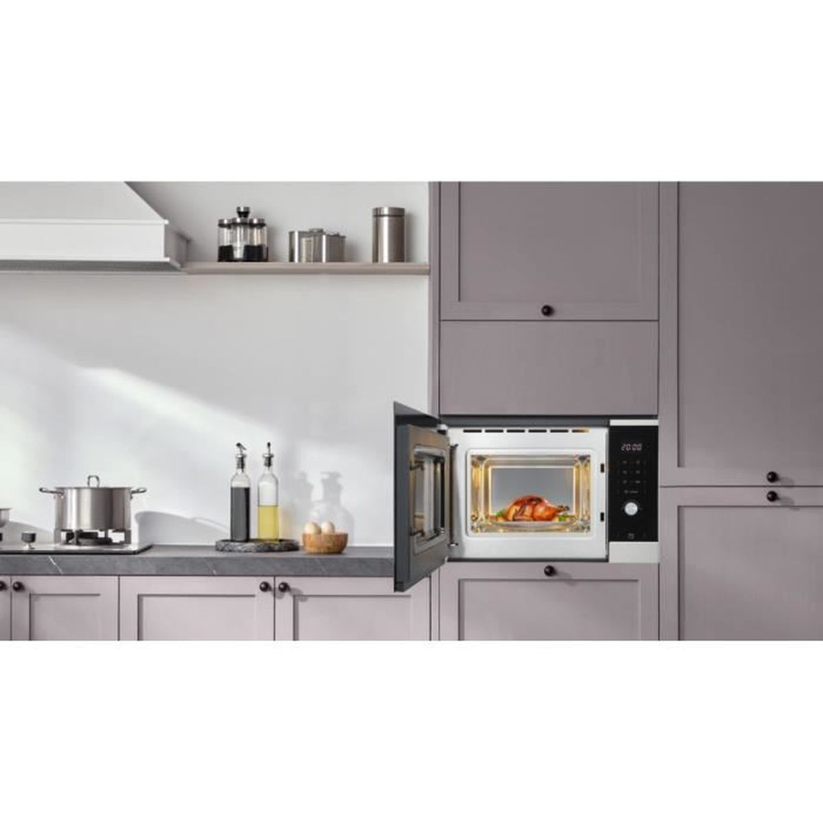 Una cucina moderna presenta un microonde da incasso con la porta aperta che mostra un pollo arrosto.