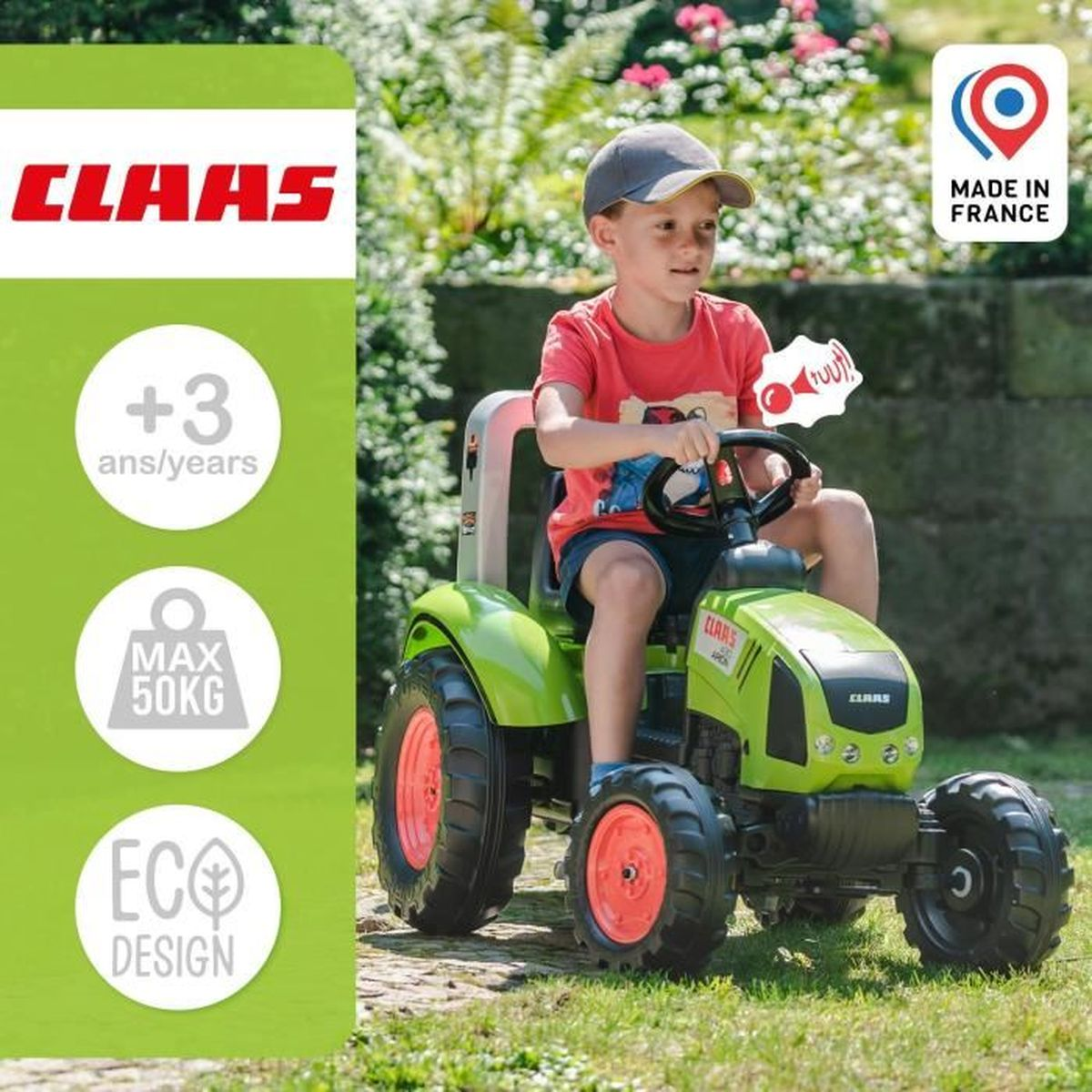 Ein kleiner Junge fährt draußen im Gras einen grünen Spielzeugtraktor.