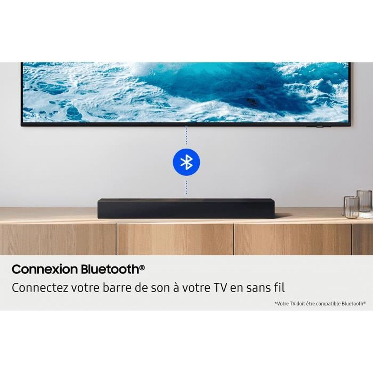 Eine schwarze Soundbar auf einem Holzschrank unter einem Fernseher mit Bluetooth-Symbol.