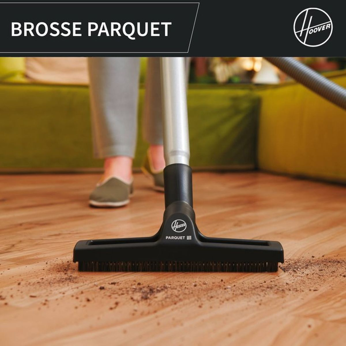 Un aspirapolvere con spazzola per parquet pulisce lo sporco dai pavimenti in legno. Un divano.