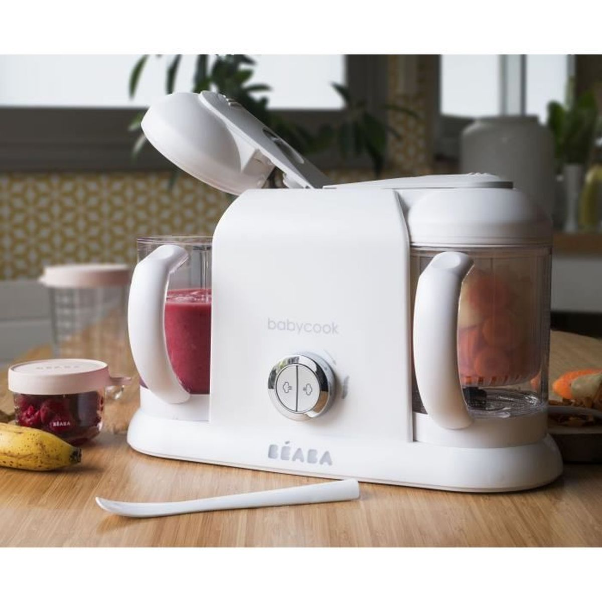 Un cuocipappa e frullatore Beaba Babycook bianco su un tavolo di legno, circondato da frutta e contenitori.