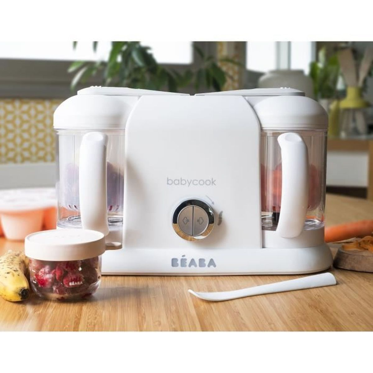 Una vaporiera Beaba Babycook bianca su un tavolo di legno, circondata da frutta e verdura.