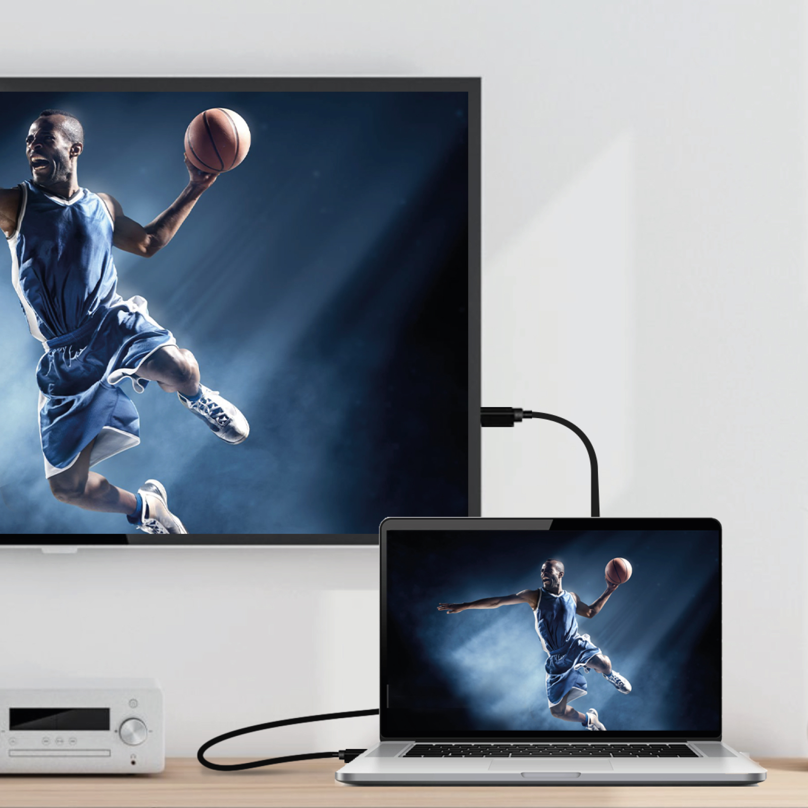 Una computadora portátil está conectada a una pantalla grande, ambas muestran al mismo jugador de baloncesto.